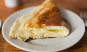 Puszysty omlet na parze, złożony na pół, z kremowym wnętrzem, podany na białym talerzu.