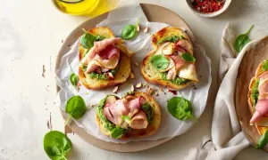 Aromatyczne kanapki z pesto, szynką i świeżą bazylią, posypane migdałami. Idealne na szybką przekąskę.