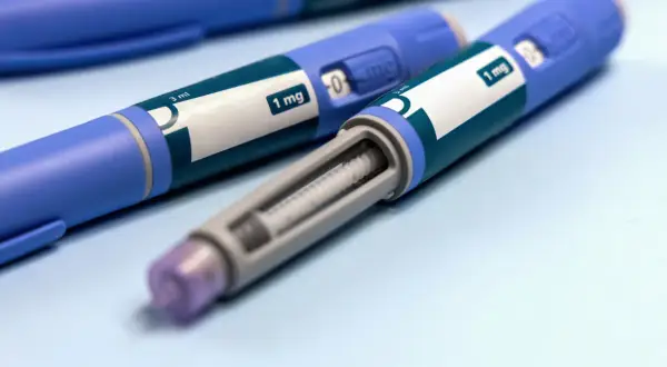 Dwa niebieskie peny z zielonymi etykietami z napisem "1 mg" i widocznym wkładem.