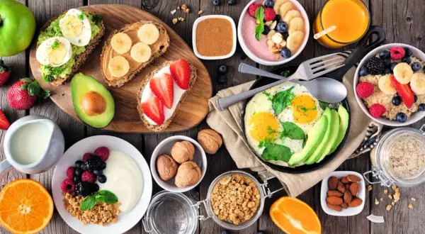 Różnorodne, zdrowe śniadanie: tosty z awokado i jajkiem, owsianka, jogurt z owocami, jajecznica, smoothie bowl.
