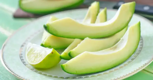 Plasterki awokado i ćwiartka limonki na talerzu. Zdrowe tłuszcze i niskie avocado kalorie.