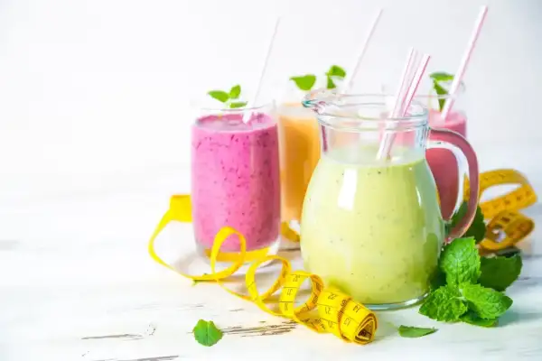Kolorowe smoothie, w tym koktajl z ananasa, z miętą i miarką, idealne na zdrową dietę.