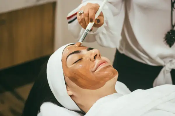 Kobieta z maską na twarzy, przygotowująca się do zabiegu hydrodermabrazji.